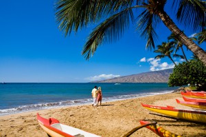 Maui "The Magic Isle" - Couple walking along the beach with canoes in the foreground